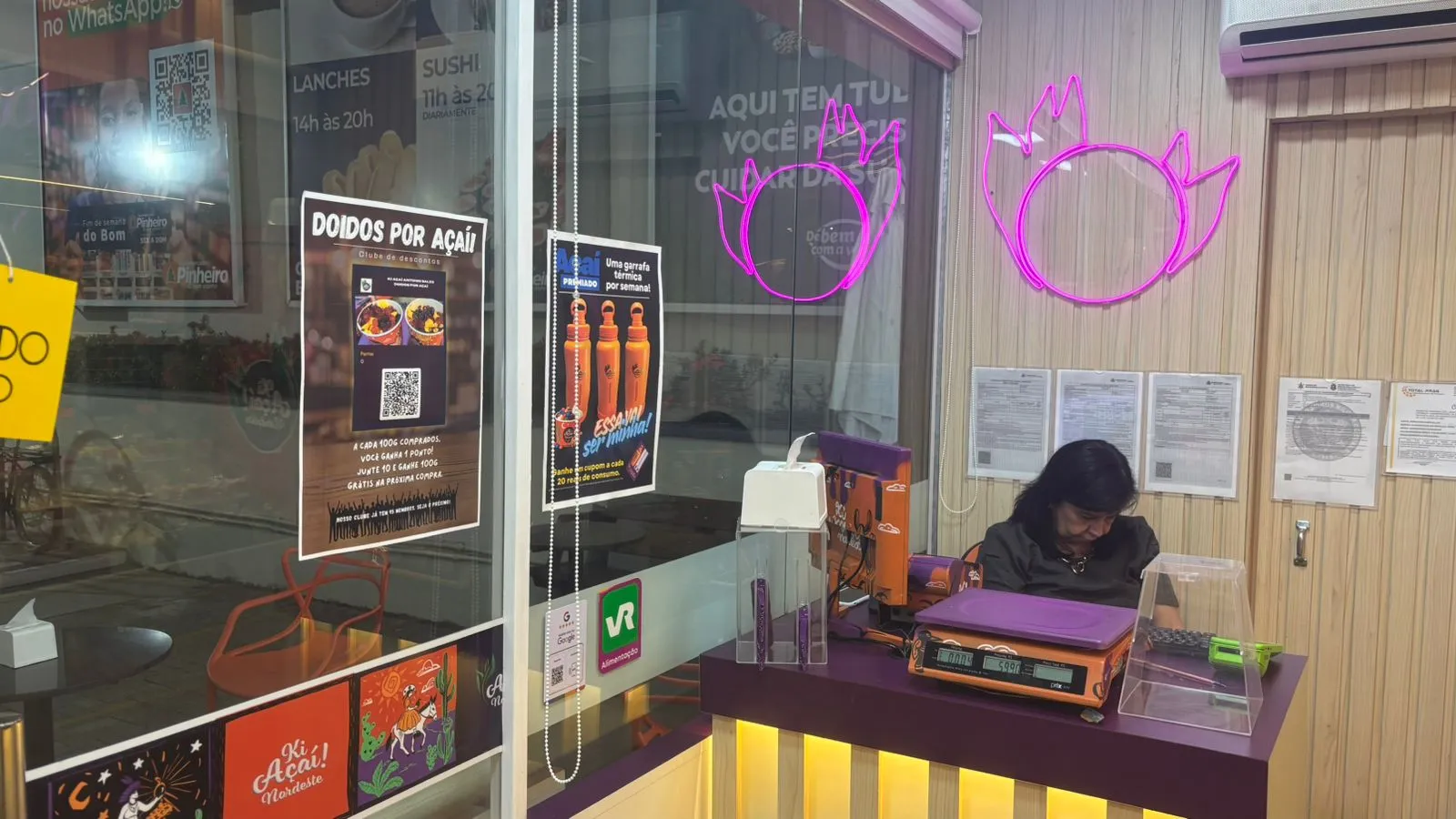Ki Açaí store front with neon açaí leaves and staff at the counter