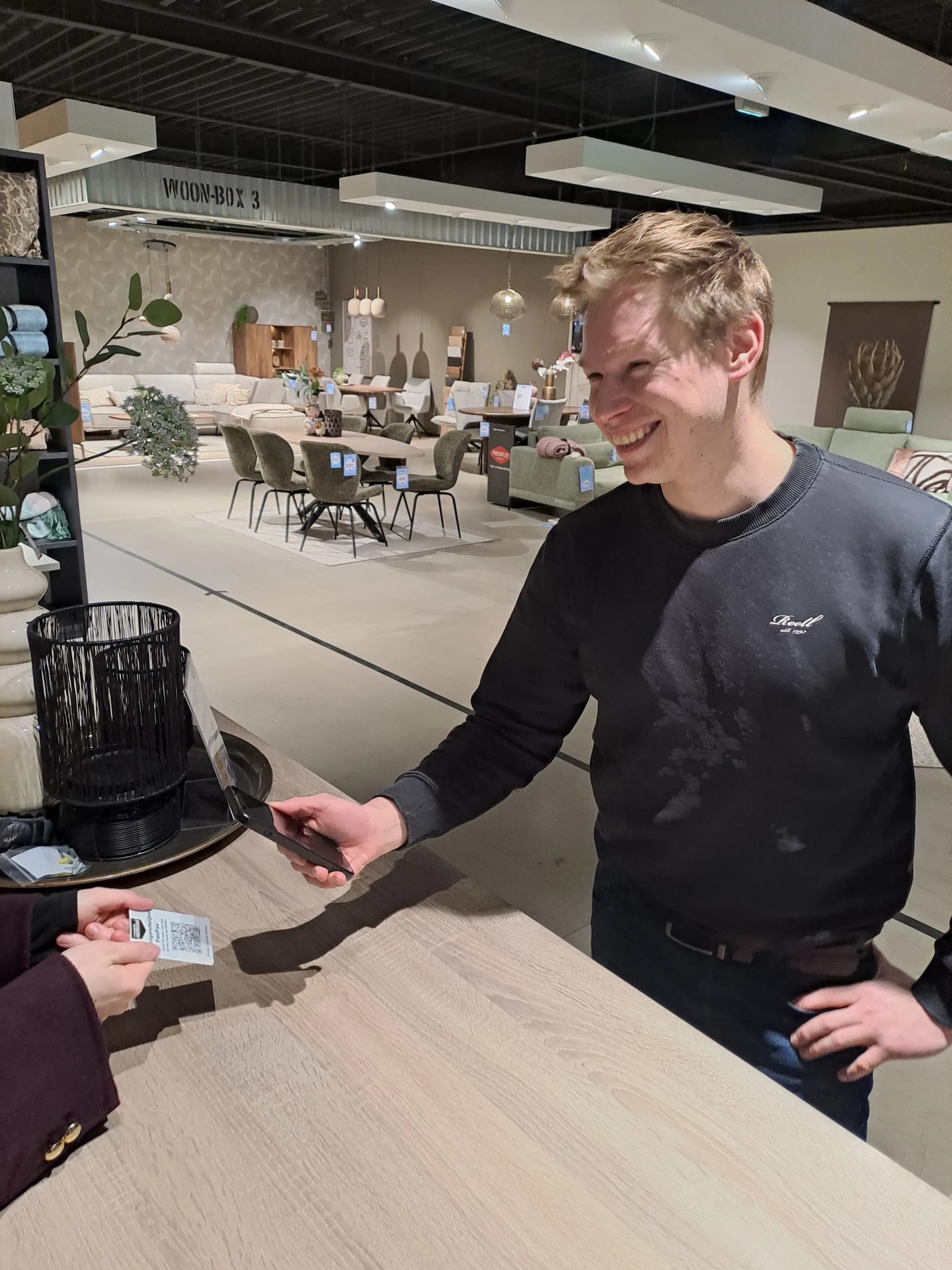 Een verkoopmedewerker overhandigt een kortingsbon-kaart aan een klant